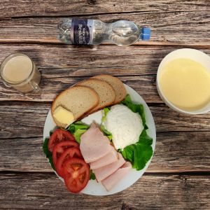 Zdjęcie przedstawia Dietę podstawową: Kawa zbożowa z mlekiem kasza kukurydziana na ml Chleb mieszany pszenno-żytni Masło extra Sałata zielona Szynka Piastowska Twarożek z koperkiem Woda mineralna Pomidor